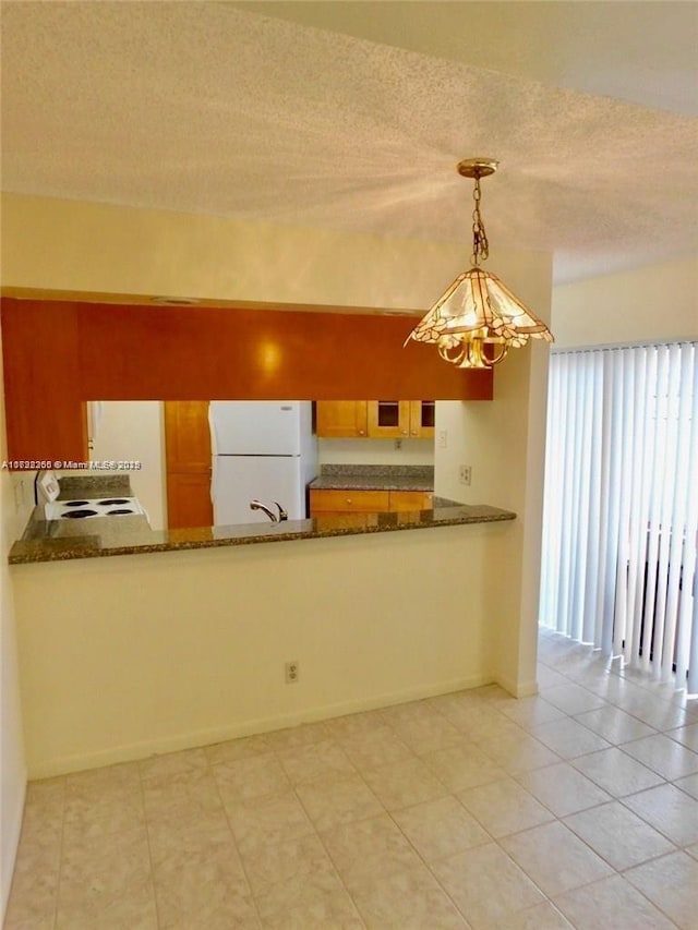 kitchen featuring white appliances, hanging light fixtures, dark stone countertops, a textured ceiling, and light tile patterned flooring