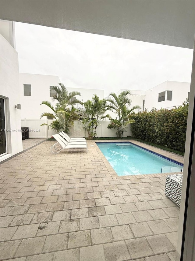 view of swimming pool featuring a patio, fence, and a fenced in pool