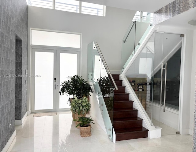 tiled foyer entrance with french doors, stairway, and a towering ceiling