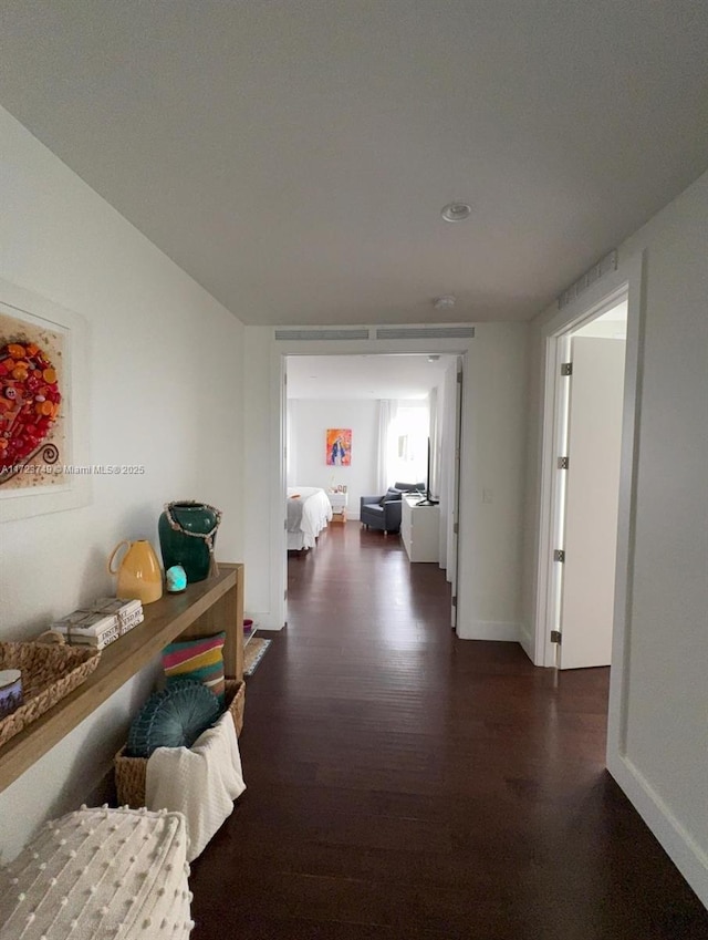 corridor featuring dark wood finished floors and baseboards