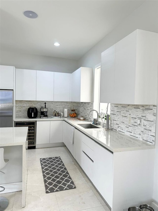 kitchen with light countertops, white cabinets, beverage cooler, a sink, and stainless steel built in refrigerator