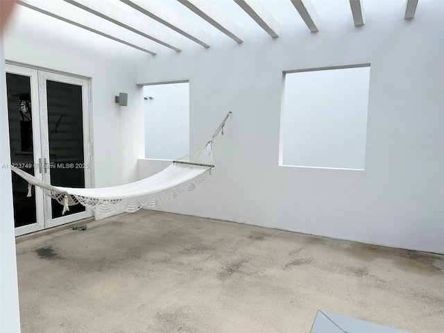 interior space with concrete flooring, french doors, and beamed ceiling