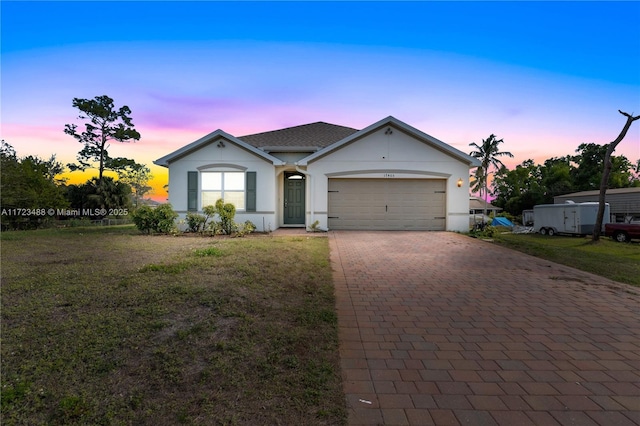 single story home featuring a garage and a lawn