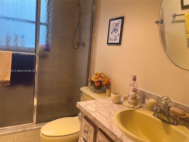 bathroom featuring tile patterned flooring, vanity, a shower with shower door, and toilet