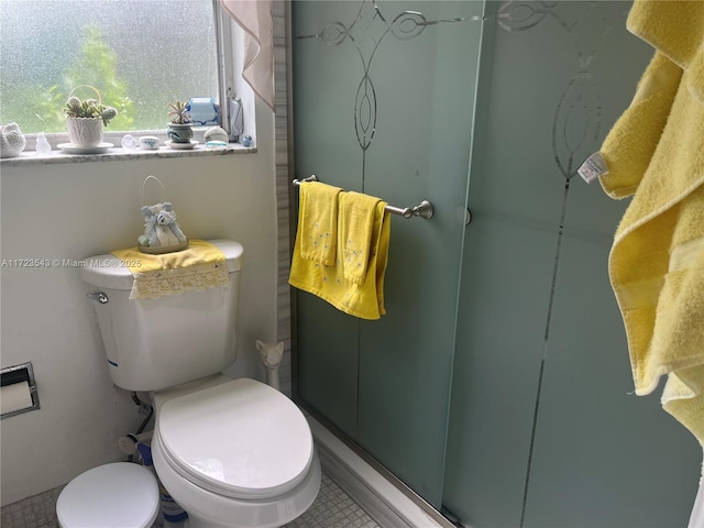 bathroom featuring tile patterned floors, a shower with door, and toilet