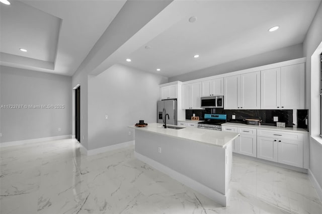 kitchen with a kitchen island with sink, sink, tasteful backsplash, white cabinetry, and stainless steel appliances