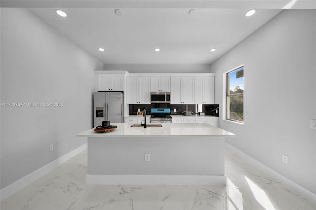 kitchen with white cabinets, stainless steel appliances, and a kitchen island with sink