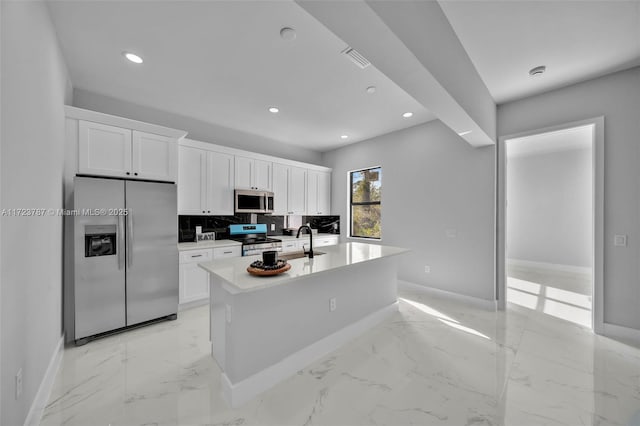 kitchen with backsplash, white cabinets, sink, an island with sink, and appliances with stainless steel finishes