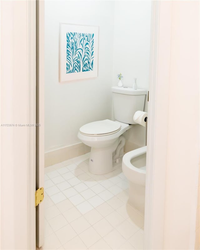 bathroom featuring tile patterned flooring, toilet, and a bidet