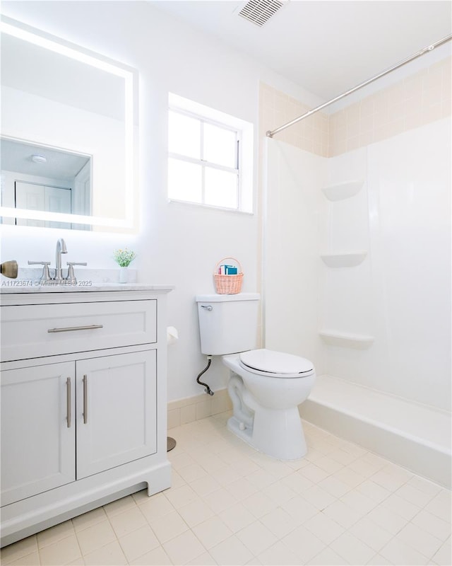 bathroom featuring tile patterned flooring, vanity, toilet, and walk in shower