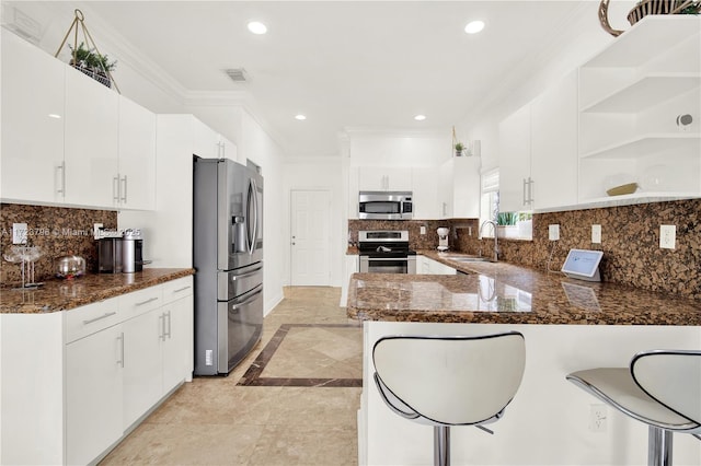 kitchen featuring appliances with stainless steel finishes, white cabinets, kitchen peninsula, and sink