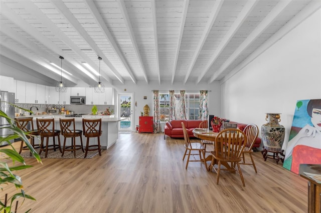 dining area with beam ceiling and light hardwood / wood-style floors