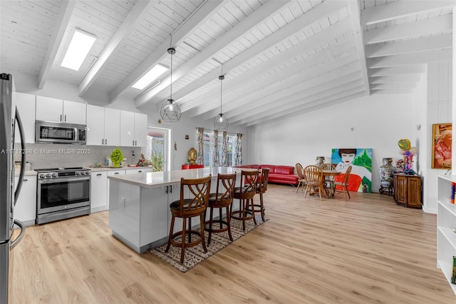 kitchen featuring white cabinetry, backsplash, stainless steel appliances, a center island, and decorative light fixtures