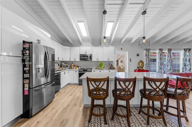 kitchen featuring white cabinetry, pendant lighting, beam ceiling, and stainless steel appliances