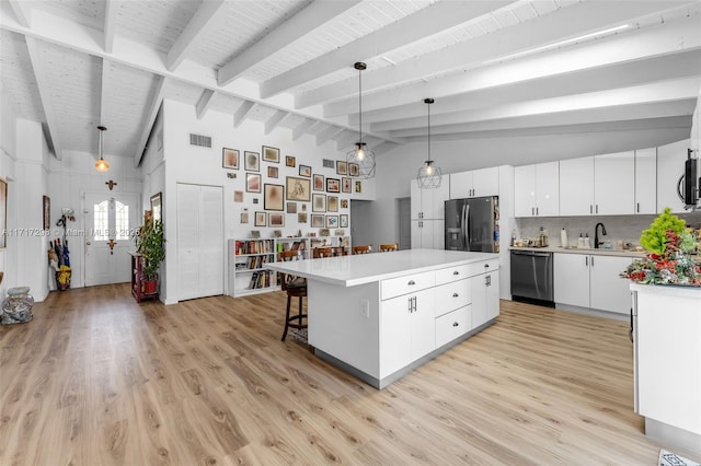 kitchen with white cabinetry, stainless steel appliances, a center island, lofted ceiling with beams, and decorative light fixtures