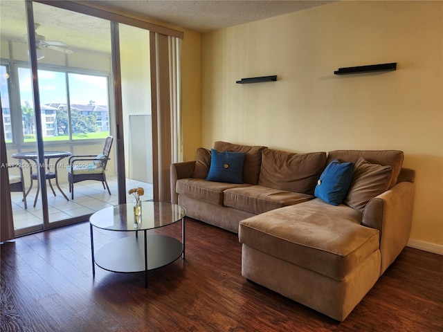 living room with a textured ceiling, ceiling fan, and dark hardwood / wood-style floors