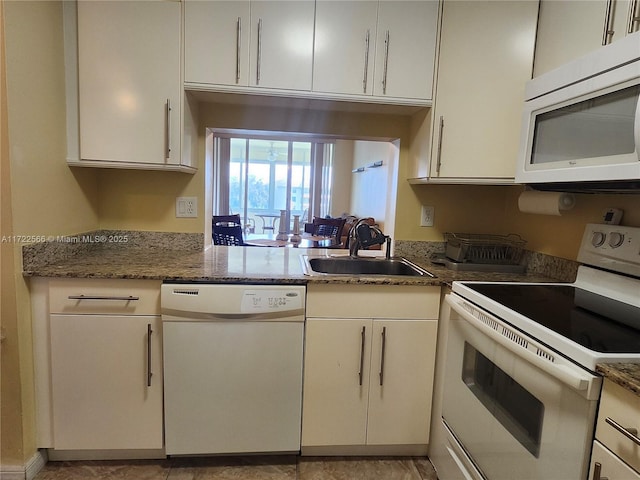 kitchen with white cabinetry, white appliances, sink, and dark stone counters