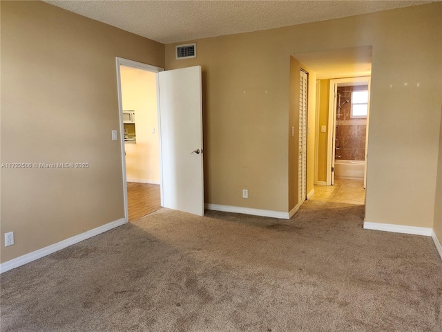 spare room featuring light carpet and a textured ceiling