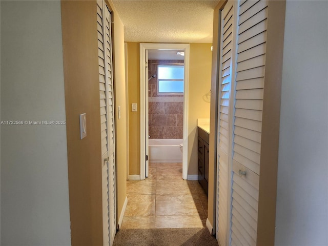 hall with light tile patterned floors and a textured ceiling