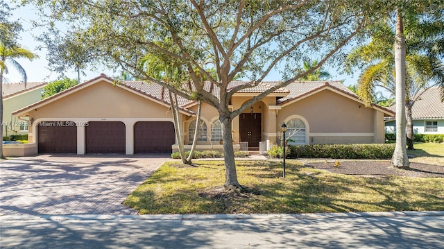 view of front of property with central air condition unit, a front yard, and a garage