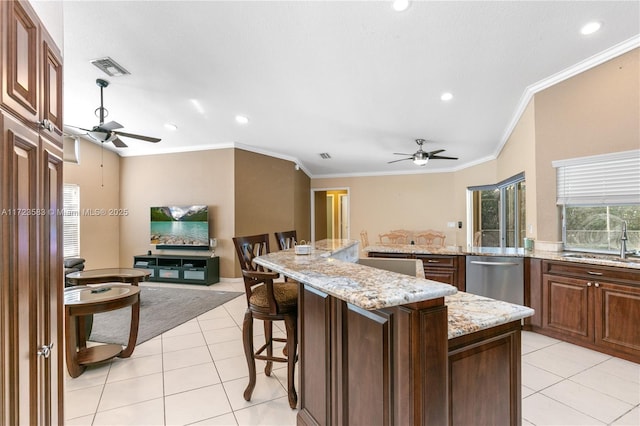 kitchen with light stone countertops, stainless steel dishwasher, sink, light tile patterned floors, and a center island