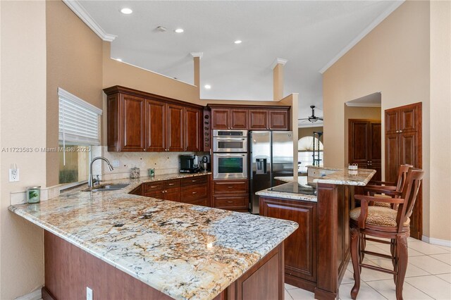 kitchen with a center island, sink, light stone counters, a kitchen bar, and appliances with stainless steel finishes