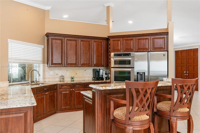 kitchen with light stone countertops, appliances with stainless steel finishes, a center island, and sink