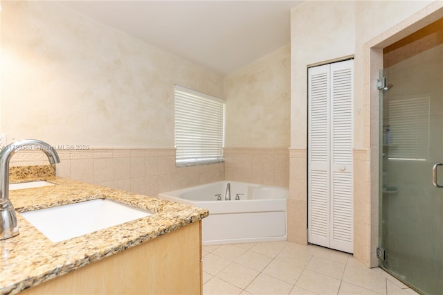 bathroom featuring tile patterned flooring, vanity, independent shower and bath, and tile walls