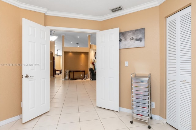 hall with ornamental molding and light tile patterned flooring