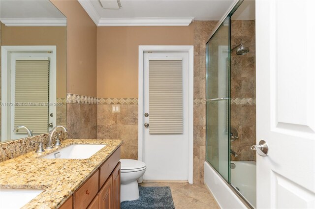 full bathroom featuring vanity, shower / bath combination with glass door, crown molding, tile patterned flooring, and toilet