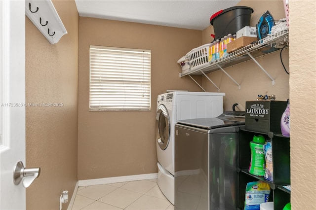 washroom with light tile patterned floors and washing machine and dryer