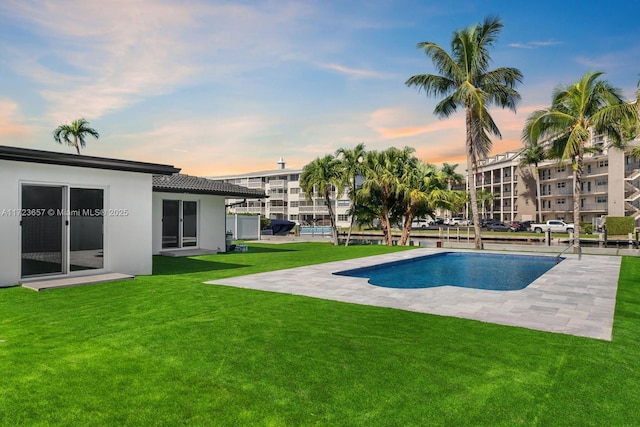 pool at dusk with a patio and a yard