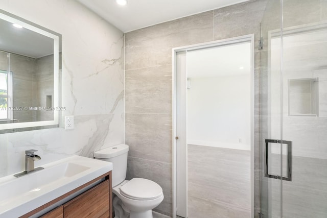 bathroom featuring vanity, toilet, tile walls, and walk in shower