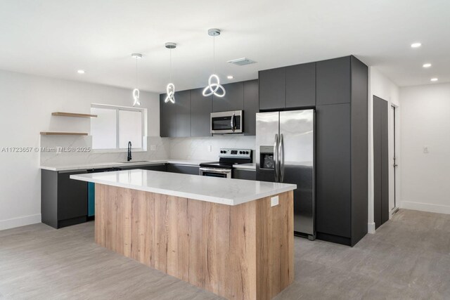 kitchen featuring hanging light fixtures, sink, a center island, and appliances with stainless steel finishes