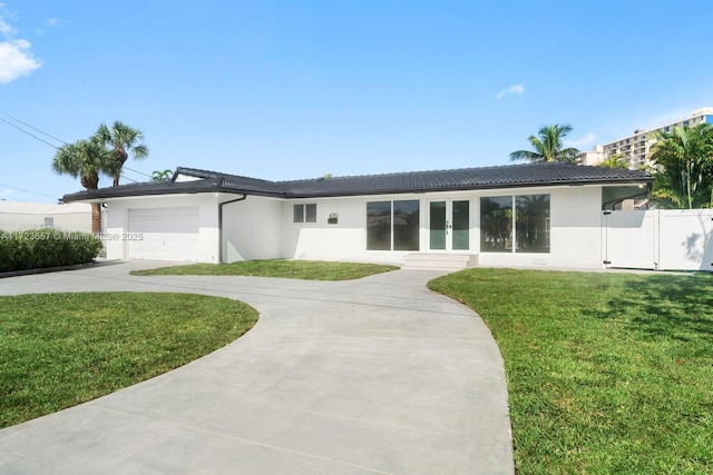 single story home with a garage, a front lawn, and french doors