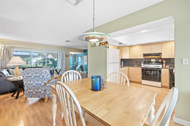 dining area featuring light hardwood / wood-style flooring and a raised ceiling