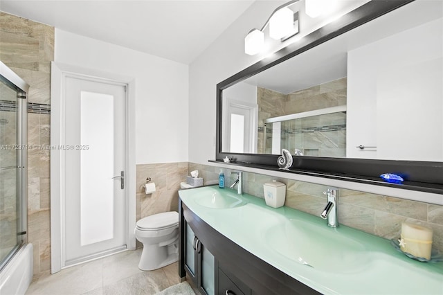 full bathroom featuring vanity, toilet, shower / bath combination with glass door, and tile walls