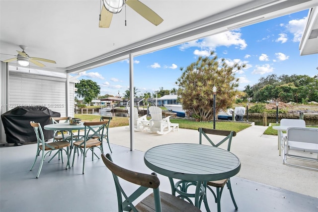 view of patio with ceiling fan, area for grilling, and a water view