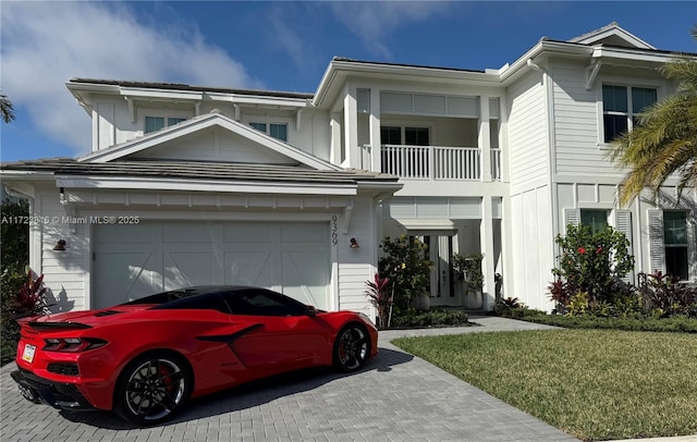 view of front of home featuring a balcony, a front yard, and a garage