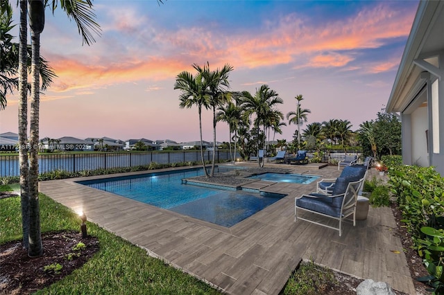 pool at dusk with a water view and an in ground hot tub