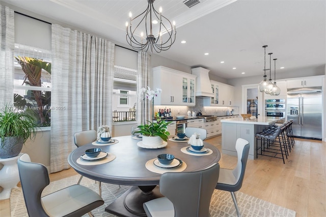 dining room with light wood-type flooring, an inviting chandelier, and sink