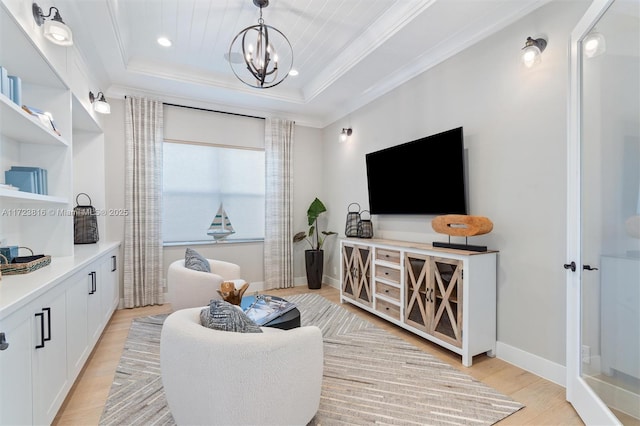 living room with ornamental molding, light hardwood / wood-style floors, a raised ceiling, and a notable chandelier