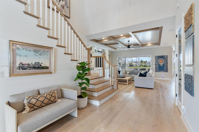 interior space with a high ceiling, beamed ceiling, light wood-type flooring, ceiling fan, and coffered ceiling