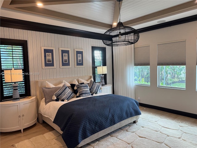 bedroom with a chandelier, beam ceiling, and light hardwood / wood-style flooring