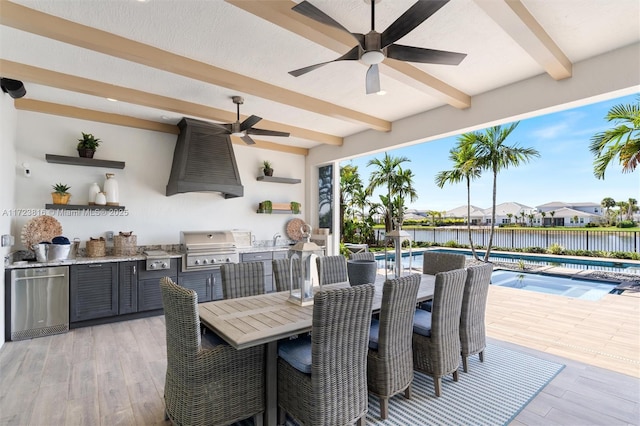 view of patio featuring area for grilling, sink, a water view, an outdoor kitchen, and a fenced in pool