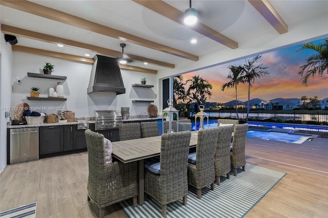 patio terrace at dusk featuring exterior kitchen, a wooden deck, and grilling area