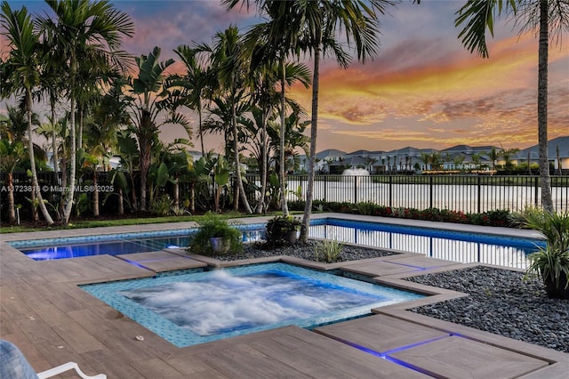 pool at dusk with an in ground hot tub