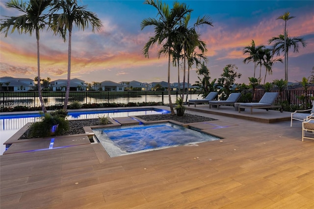 pool at dusk featuring a community hot tub