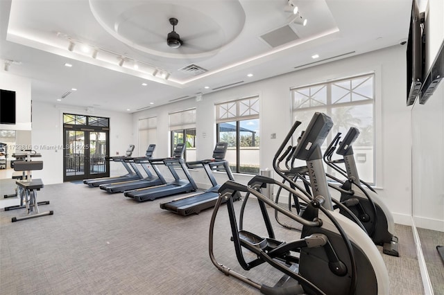 gym featuring ceiling fan, french doors, and a tray ceiling