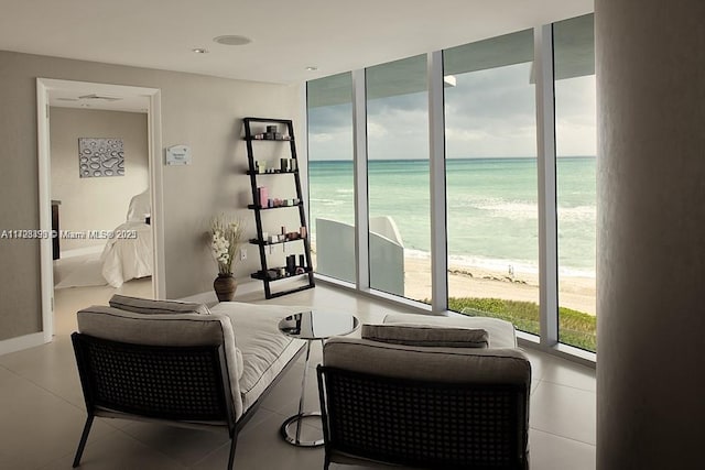 living room featuring expansive windows, a water view, a beach view, and a wealth of natural light